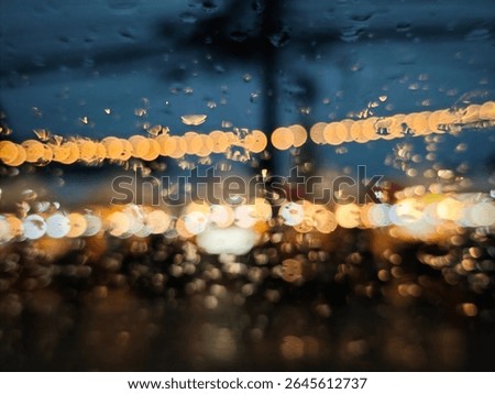 Abstract bokeh background with warm string lights seen through a rain-covered window at night, Blurred city street scene with droplets on glass.