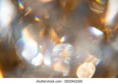 Abstract bokeh effect background of transparent gem in golden frame with rainbow rays.