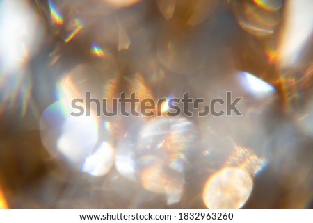 Abstract bokeh effect background of transparent gem in golden frame with rainbow rays.