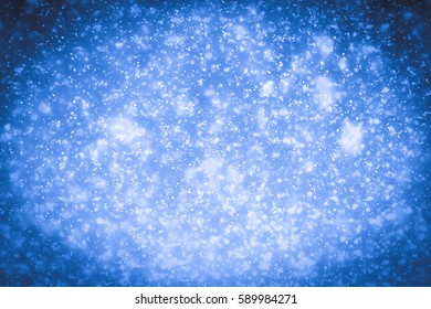 Abstract bokeh or glitter lights on blue  background. Circles and defocused particles. Design template.