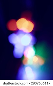 Abstract bokeh light composition with soft-focus light orbs against a deep midnight blue background. Warm peachy-gold tones at top transition to electric blue and periwinkle hues, with cool cyan and soft pink accents. Overlapping circular lights create depth and a luminous glowing effect. Evokes festivity, wonder, and nocturnal mystery, ideal for holiday campaigns or nightlife collateral.