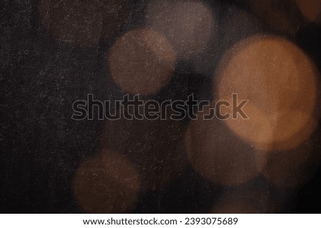 Abstract bokeh texture background with orange and brown circles from a garland on a dark antique backdrop close up. Circles of different sizes, blurred and out of focus. Free space for text.
