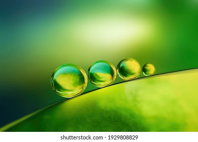 Abstract Bright Colorful Background With Drops Of Oil And Water In Green And Yellow Tones, Macro. Creative Image Of The Beauty Of Environment And Nature.