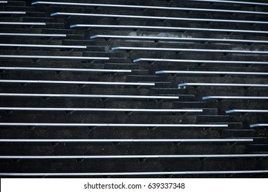 Abstract Brutal Modernism Concrete Sports Stadium With Horizontal Rows Of Aluminum Bleacher Benches Divided By Diagonal Aisle Of Stairs