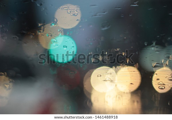 An abstract car window on a rainy day, viewed\
from the seat in the car, blurred background in the evening, rain\
in the car window, blurred rain in the car window, driving light in\
rainy weather