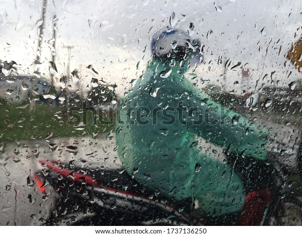 Abstract car window in raining day. View from\
car seat. Blur Background at sunset. Drops of rain on car window\
pane. Blurred droplet on car window, sun light over empty road.\
Driving in rain\
weather.\

