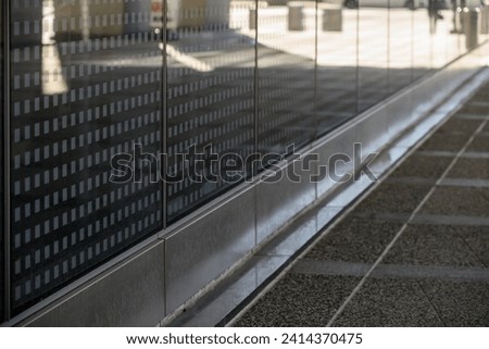 Abstract city street scene Glass office building windows reflecting paved walkway with a woman walking in the distance.