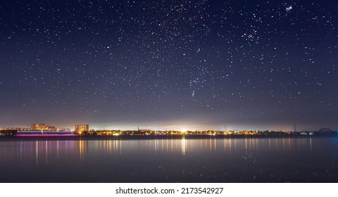 Abstract Cityscape With Modern High Rise Buildings Skyscrapers And City Lights Reflected In Mirror Water Surface Of Calm River Or Lake At Dark Night. With No People Ukraine Dnipro City On Dnipro River