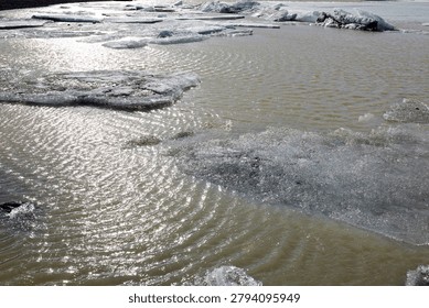 Abstract close up of floating ice sheets and sparkling water reflection in a glacier lagoon in horizontal Iceland view