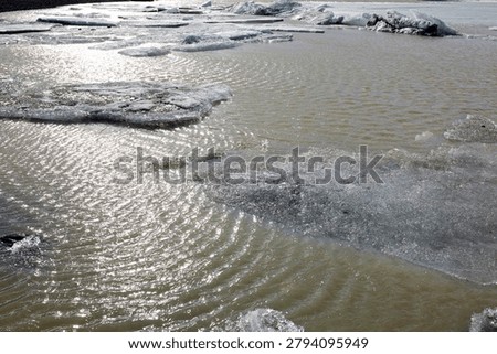 Abstract close up of floating ice sheets and sparkling water reflection in a glacier lagoon in horizontal Iceland view