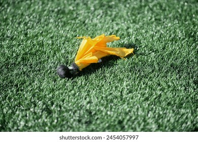 abstract close up of a refrees penalty flag  on a artificial turf field  - Powered by Shutterstock