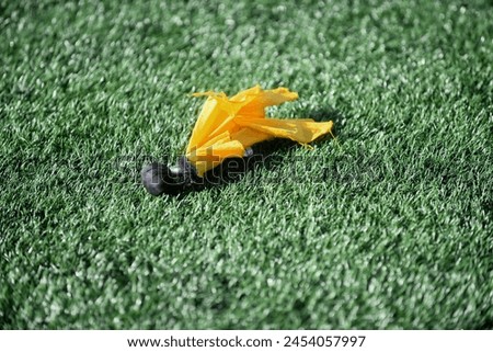 abstract close up of a refrees penalty flag  on a artificial turf field 