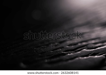 Abstract Close-Up of Dark Textured Surface with Shiny Highlights and Shadows