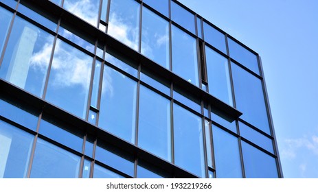 Abstract Closeup Of The Glass-clad Facade Of A Modern Building Covered In Reflective Plate Glass. Architecture Abstract Background. Glass Wall And Facade Detail.