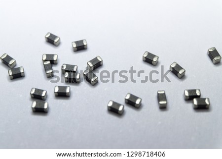 Abstract close-up of grey scattered 0402 SMT surface mount chip ferrite bead power electronics components on white background in random pattern