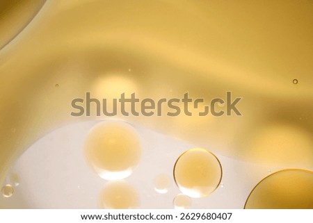 An abstract close-up image showcasing the interplay of oil and water with soft golden highlights and glowing bubbles. Ideal for artistic design projects.