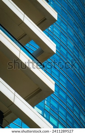 Abstract close-up of a modern glass building with reflective windows and contrasting white ledges