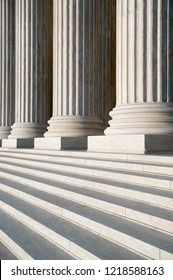 Abstract close-up of the neoclassical white marble fluted columns with steps at the entrance to the US Supreme Court Building in Washington DC