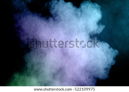 Abstract colored powder on a black background. Frozen abstract movement of dust explosion multiple colors on a black background. Stop the movement of multicolored powder on a dark background.