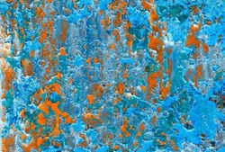 Abstract Colorful Background Of A Corroded Metallic Surface With Flaking Paint Converted Into Negative. Vibrant Colors In Bright Blue, Orange And Turquoise.