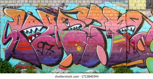 Abstract colorful fragment of graffiti paintings on old brick wall. Street art composition with parts of unwritten letters and multicolored stains. Subcultural background texture