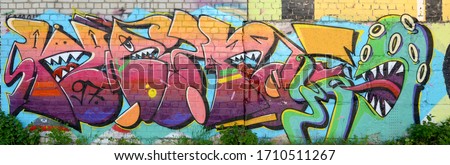 Abstract colorful fragment of graffiti paintings on old brick wall with scary octopus face. Street art composition with parts of unwritten letters and cartoon character