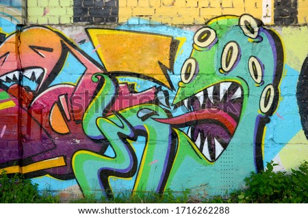 Abstract colorful fragment of graffiti paintings on old brick wall with scary octopus face. Street art composition with parts of unwritten letters and cartoon character