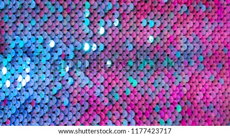 Abstract colorful Texture scales with bright Sequins close-up. Glamor Background with shiny blue, purple and Magenta sequins on fabric, macro. Beautiful Holiday Wallpaper with pattern of round Sequins