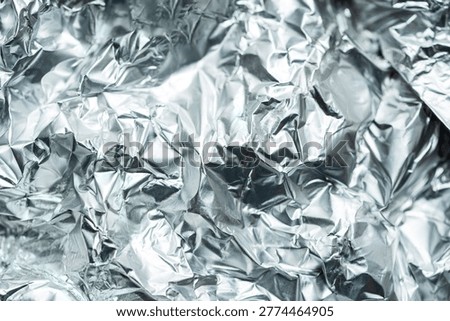 Abstract composition featuring a close up of crumpled aluminum foil with reflective highlights and deep shadows.