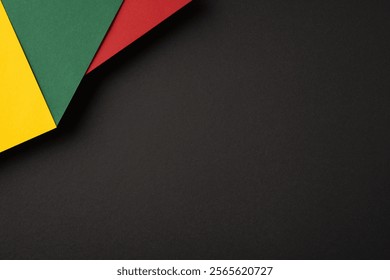 Abstract composition featuring red, green, and yellow paper sheets overlapping on a dark backdrop, creating contrast