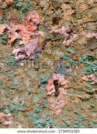 An abstract composition featuring scattered, thick paint fragments and smears in vibrant reds, yellows, blues, and purples resting on a textured greenish surface. The image evokes a sense of raw creativity, spontaneity, and the tactile beauty of dried pigments and layered brushstrokes.