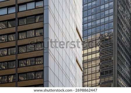 An abstract composition showcases the various contrasting materials, brightness, color, materials, and geometric patterns of the windows of various skyscrapers in New York City, New York