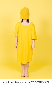 Abstract Concept Of Anxiety, Depression And Stress On Childhood Concept. Little Girl Wearing Over Size Shirt And Blindfolded With Hat Isolated On Yellow Background