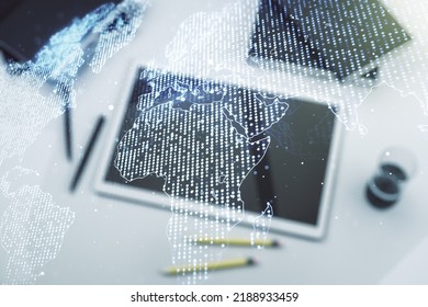 Abstract creative digital world map and modern digital tablet on desktop on background, top view, globalization concept. Multiexposure