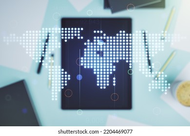 Abstract creative digital world map and modern digital tablet on desktop on background, top view, globalization concept. Multiexposure