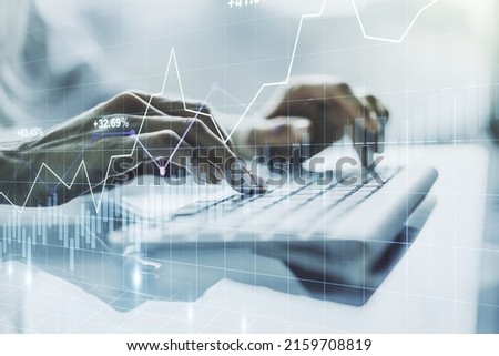 Abstract creative financial graph with hand typing on laptop on background, financial and trading concept. Multiexposure