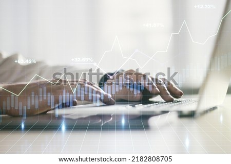 Abstract creative financial graph with hand typing on laptop on background, forex and investment concept. Multiexposure