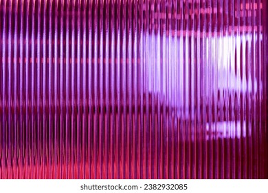 Abstract creative image on patterned glass show vertical lines pattern repetition blurry background of wavy illuminated multi-colored interior soft lighting.glass surface used for artistic backdrop.