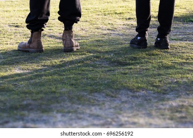 
An Abstract Crop Of Two Blue Collar Workers As They Stand Next To Each Other On Grass In Morning Sun Light.