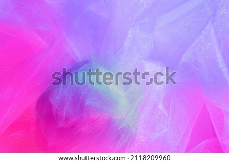 Abstract cyberpunk fashion blog concept. Light pink tulle fabric enlightened with two colors – blue and red. Background from pink crumpled tulle. Textured background for atelier.