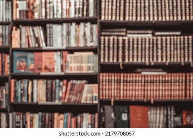 Abstract Dark Blurred Background Of Bookshelves With Books In Library Or In Book Store, Soft Focus. Concept Of Reading, School, Culture, Education