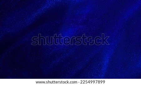 Abstract defocused blue background with silver dust particles. Defocused Lights and Glowing Dust Particles with depth of field. Blue background with shimmering glitter particles.