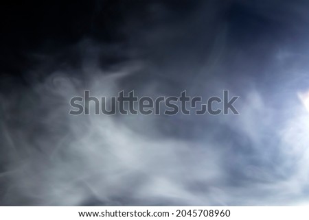 Abstract design of white cloud on a dark background. Blurry motion of smoke.