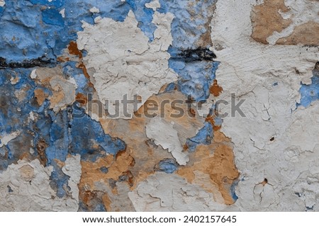 Abstract, detail, pattern of a section of multi-colored, peeling blue and yellow paint layers on an old stone exterior wall of a residence in Jerusalem, Israel.