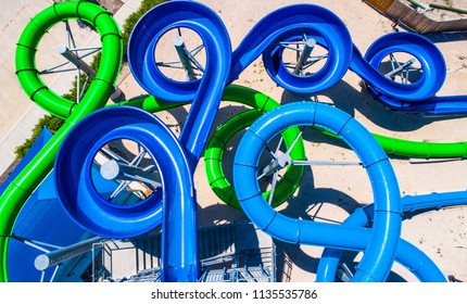 Abstract Drone View Above Curvy Blue Water Slide. Aerial Straight Down Angle Of Refreshing Summer Vacation At Waterpark