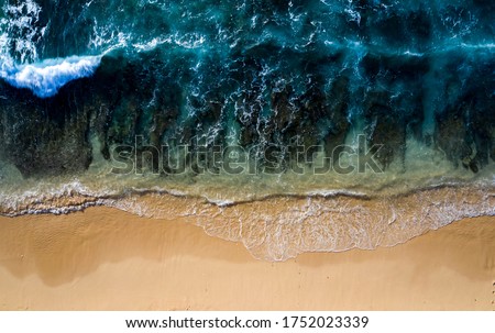 Abstract drone view taken directly from above of some tidal waves breaking along the shoreline of a beach in Bali Indonesia.