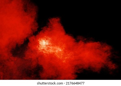 Abstract Explosion Of Orange Dust On Black Background.Freeze Motion Of Orange Powder Burst.