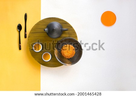Abstract flat lay mid autumn festival food and drink, mooncakes and tea on yellow and white background.