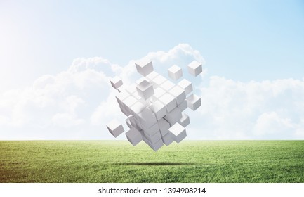 Abstract flying white cubes on green meadow. Virtual reality and digital technology. Hi-tech geometric composition. Nature landscape with green grass and blue sky. Mixed media with 3D rendering object