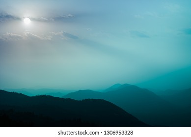 Abstract Full Blue Moon Emotinal Skyscape. Teal Pastels Of Foggy Dream Background With Soft Tiffany Blue To Hazy Purple Sky Above Mountain Tops. Sequoia National Park Forested Hills In Misty Light.